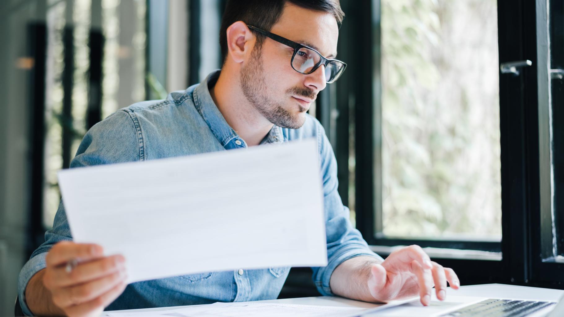 person looking at laptop and papers
